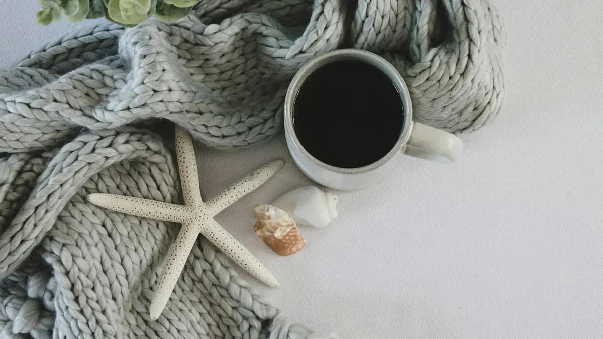 明るいグレーのニットとコーヒー